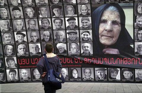 A boy pauses in front of a wall-sized poster depicting the faces of 90 survivors of the mass killings of Armenians in the Ottoman Empire, in Yerevan, Armenia